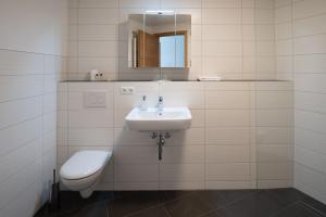 ein Badezimmer mit einem Waschbecken, einem WC und einem Spiegel in der Unterkunft Moderne Ferienwohnung direkt am Wasser in Heiligenstadt