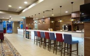 cocina con barra con sillas azules y rojas en Hampton by Hilton Moscow Strogino, en Moscú
