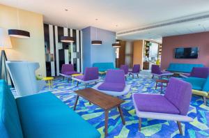 een wachtkamer met blauwe en paarse stoelen en tafels bij Hampton by Hilton Warsaw City Centre in Warschau