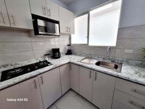 una cocina con armarios blancos y fregadero en Casa Victoria Hostel en San Isidro