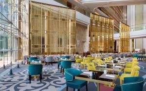 a rendering of a restaurant with yellow tables and chairs at Hilton Astana in Astana