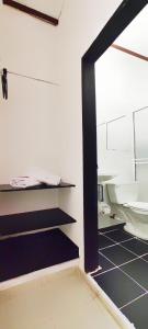 a bathroom with a toilet and a black shelf at HOTEL BUGANVILIA in Oiba