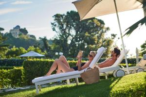 two women laying in lawn chairs under an umbrella at Rome Cavalieri, A Waldorf Astoria Hotel in Rome