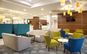 a waiting room with chairs and tables and a tv at Hampton by Hilton Nizhny Novgorod in Nizhny Novgorod