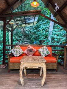an orange couch with pillows and a coffee table at Rupa Rupa High Jungle Eco B&B in Machu Picchu