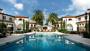 a pool in front of a building with palm trees at Bungalows at The Boca Raton in Boca Raton