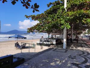 a beach with a tree and people on the beach at Amplo Apto 2sui+1Q Vista Mar 50m da Praia in Balneário Camboriú