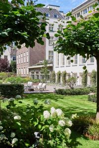 um parque com um banco em frente a um edifício em Waldorf Astoria Amsterdam em Amsterdã