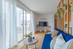 ein Wohnzimmer mit einem blauen Sofa und einem großen Fenster in der Unterkunft Ático Cholas by the Beach in San Miguel de Abona