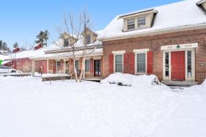 een rood bakstenen huis met sneeuw op de grond bij Stowe Mountain Road Escape in Stowe