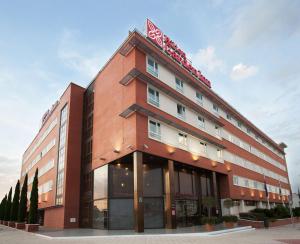 a brown building with a sign on top of it at Hilton Garden Inn Málaga in Málaga