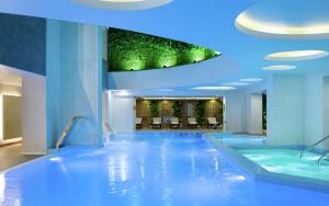 阿拉木圖的住宿－DoubleTree by Hilton Almaty，酒店大堂的游泳池,拥有蓝色的灯光