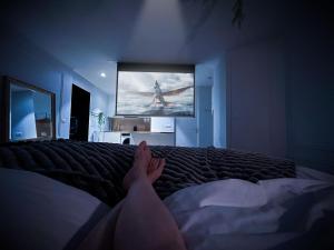 a person laying on a bed watching a tv at Le Petit Luxe - hypercentre, cinéma, king size in Troyes