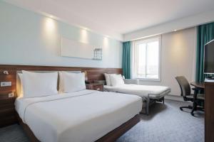 a hotel room with two beds and a desk at Hampton by Hilton Amsterdam Centre East in Amsterdam