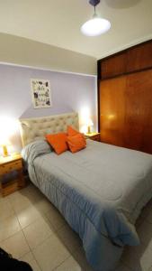 ein Schlafzimmer mit einem Bett mit zwei orangenen Kissen darauf in der Unterkunft Grandioso 2 en Barrio Sur in San Miguel de Tucumán