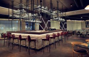 un restaurante con un bar con mesas y sillas en Hilton Belgrade en Belgrado