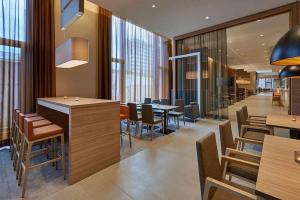 um restaurante com mesas e cadeiras de madeira e janelas em Hampton by Hilton Berlin City Centre Alexanderplatz em Berlim