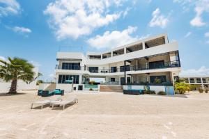 a white building on the beach with a palm tree at Playa De Sala Boutique Hotel, Adults Only in San Pedro