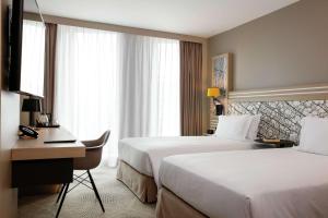 a hotel room with two beds and a desk at Hilton Garden Inn Bordeaux Centre in Bordeaux