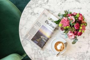 a table with a newspaper and a cup of coffee and flowers at Hilton Brussels Grand Place in Brussels