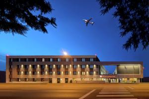 an airplane is flying over a building with a hospital at Hilton Garden Inn Bucharest Airport in Otopeni