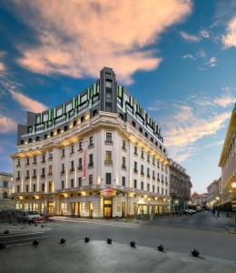 um grande edifício branco numa rua da cidade ao anoitecer em Hilton Garden Inn Bucharest Old Town em Bucareste