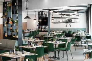 une salle à manger avec des tables et des chaises vertes dans l'établissement Hilton Garden Inn Bucharest Airport, à Otopeni