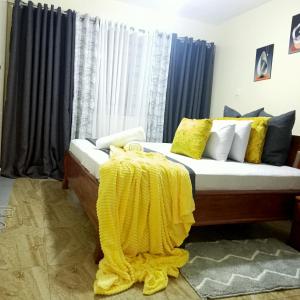 a bedroom with a bed with a yellow blanket on it at Jaymorgan' cabins in Nyeri