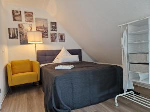 ein Schlafzimmer mit einem Bett und einem gelben Stuhl in der Unterkunft Modern-Living Stadt-Appartement Mitte in Bielefeld