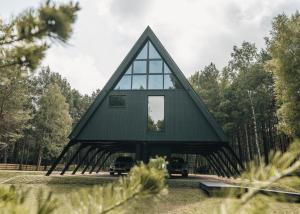 a triangular house with a gambrel roof at West House in Bernāti