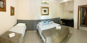 a bedroom with two beds and a desk in it at Pousada Praeros in Rifaina