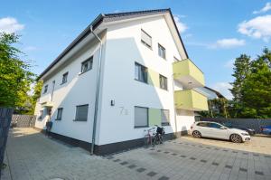 ein weißes Gebäude mit einem Auto, das daneben parkt. in der Unterkunft Großzügig & individuell - Balkon - WiFi - TV in Bielefeld