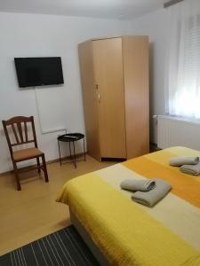 um quarto com 2 camas, uma televisão e uma cadeira em Soba LIPA em Valpovo