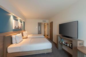 ein Hotelzimmer mit 2 Betten und einem Flachbild-TV in der Unterkunft Hampton by Hilton Düsseldorf City Centre in Düsseldorf