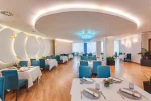 クルジュ・ナポカにあるDoubleTree by Hilton Hotel Cluj - City Plazaの白いテーブルと青い椅子が備わるレストラン