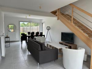 a living room with a couch and a table with a television at Nouveau! Maison avec Jacuzzi 1-8 pers à 10 mn de st Malo in Saint-Méloir-des-Ondes