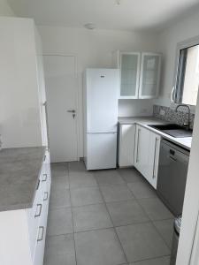 uma cozinha branca com electrodomésticos brancos e armários brancos em Nouveau! Maison avec Jacuzzi 1-8 pers à 10 mn de st Malo em Saint-Méloir-des-Ondes
