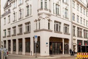un bâtiment blanc dans une rue de la ville avec des gens debout à l'extérieur dans l'établissement FeelgooD Apartment COZY Leipzig CityCenter mit TG-Stellplatz, à Leipzig