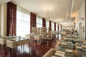un ristorante con tavoli e sedie bianchi e una grande finestra di Hilton Florence Metropole a Firenze