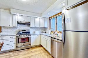 La cuisine est équipée de placards blancs et d'un réfrigérateur en acier inoxydable. dans l'établissement Eagle Ridge House, à Bartlett