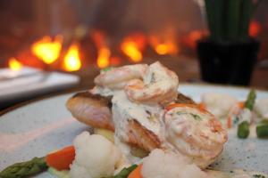a plate of food with shrimp and vegetables in front of a fireplace at Hilton Garden Inn Frankfurt City Centre in Frankfurt