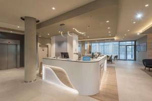美因河畔法兰克福Hampton By Hilton Frankfurt Airport的办公室大堂设有白色柜台和椅子