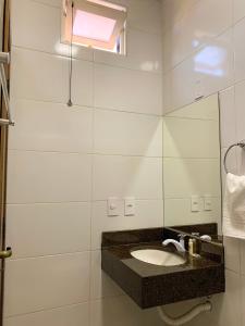 a bathroom with a sink and a mirror at Pousada Praeros in Rifaina