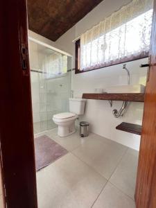 a bathroom with a toilet and a shower and a sink at Casa Cambuí Hospedagem Rural in São José do Rio Preto