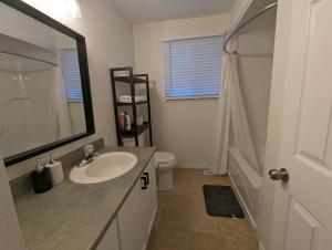 ein Badezimmer mit einem Waschbecken, einem WC und einem Spiegel in der Unterkunft Adorable 4 bed,2 bath house in Kingston