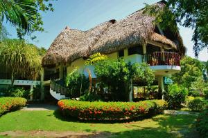 a house with a thatched roof and a flower garden at Casa Guardia Panama in Playa Blanca