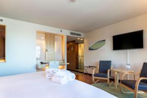 a bedroom with a white bed with two chairs and a tv at Hilton Helsinki Airport in Vantaa