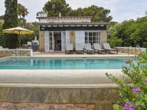 una piscina di fronte a una casa con sedie e ombrellone di Belvilla by OYO Blu Marine a Font de Sa Cala