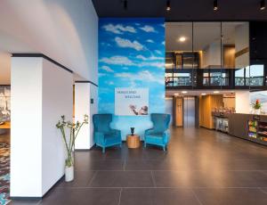 un vestíbulo con 2 sillas y un mural de cielo azul en Hampton by Hilton Istanbul Kurtkoy, en Estambul