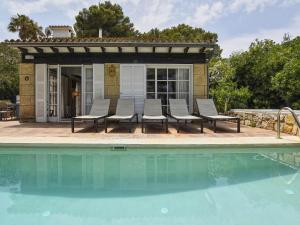 a group of chairs sitting next to a swimming pool at Belvilla by OYO Blu Marine in Font de Sa Cala